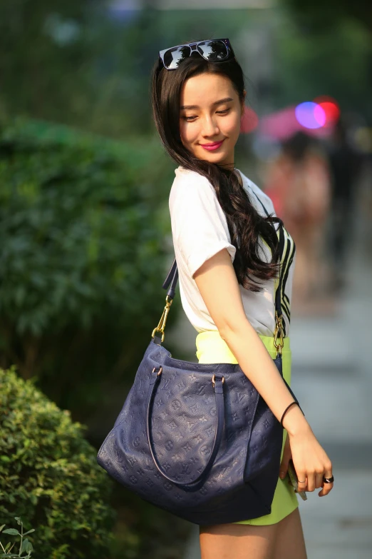 a young lady carrying a purple bag walking on the sidewalk