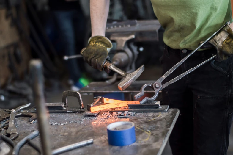 a person is using two tongs to work on a piece of metal