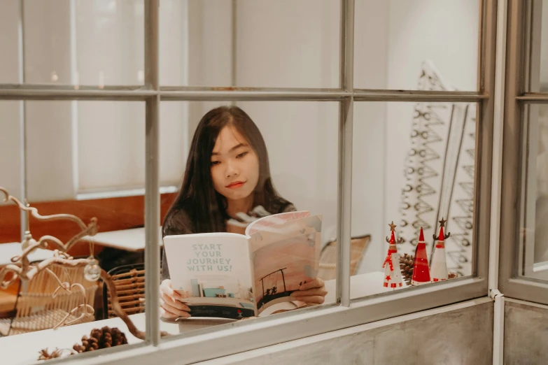 a  is reading her book at the window sill