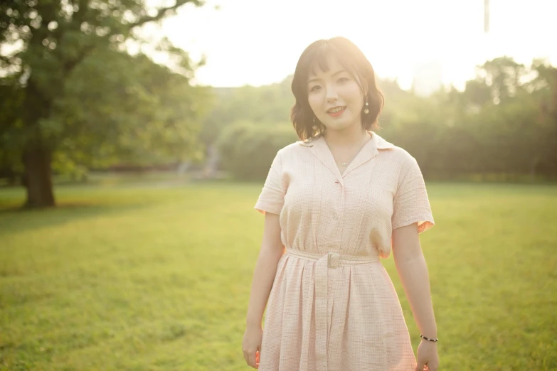 woman in an dress smiling at the camera with trees in the background