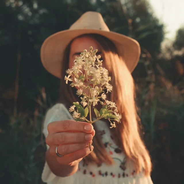 a woman holding a flower with her right hand