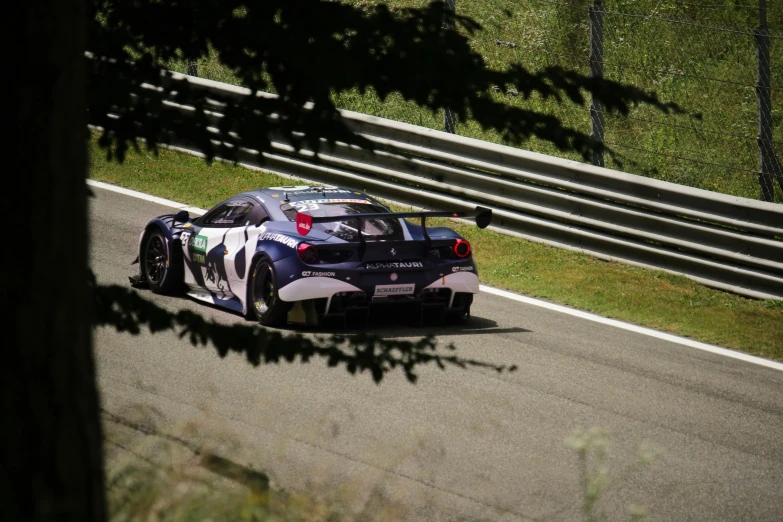 the race car driving on a road with grass behind it