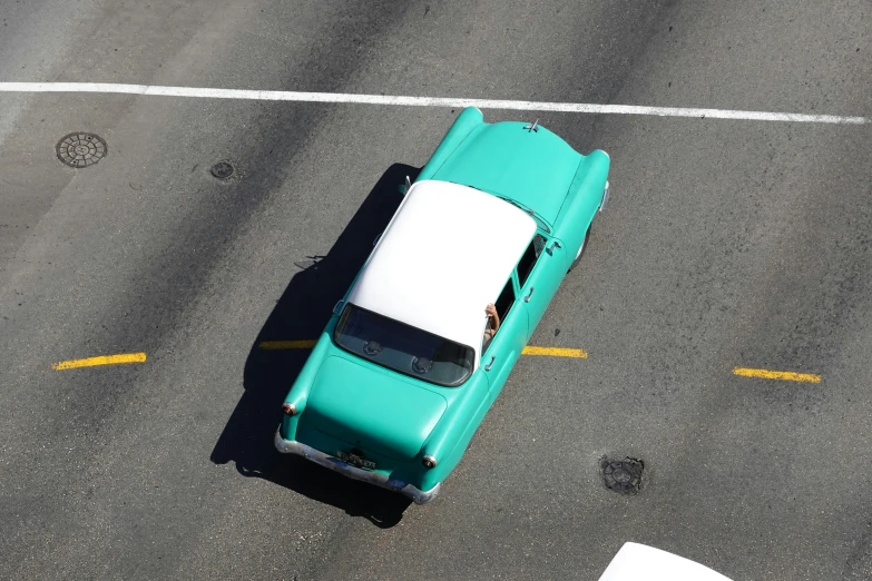 a view of a very bright turquoise car driving through traffic