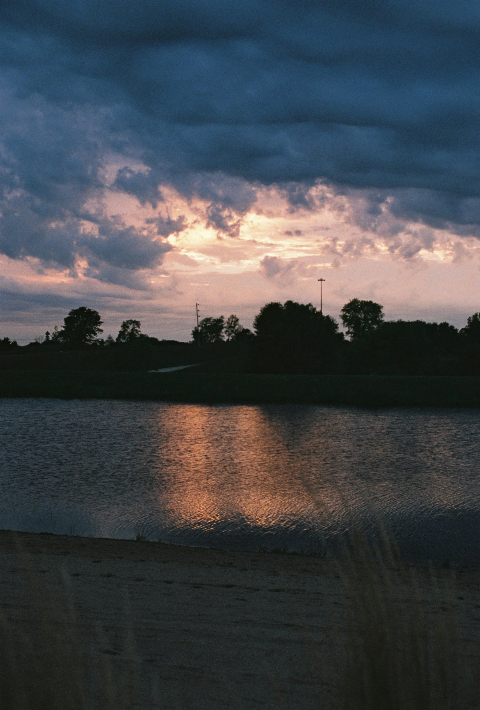 the sun shines through a cloudy sky above water