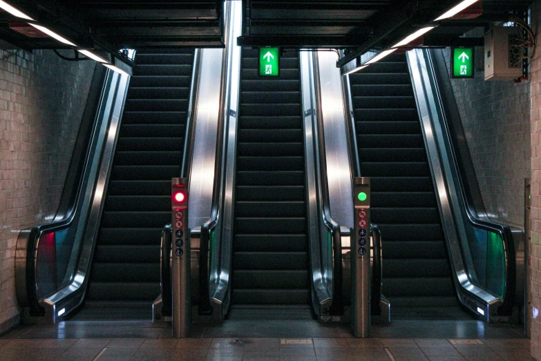 three escalators with green arrows in between them