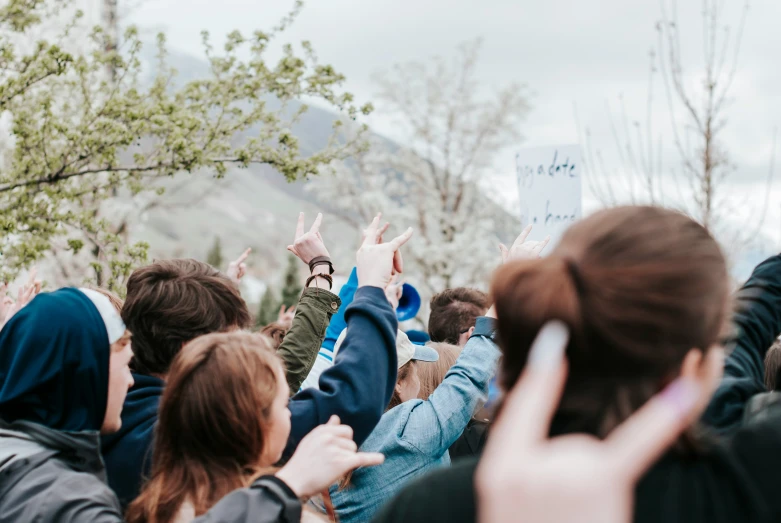 several people are raising their hands in front of a tree