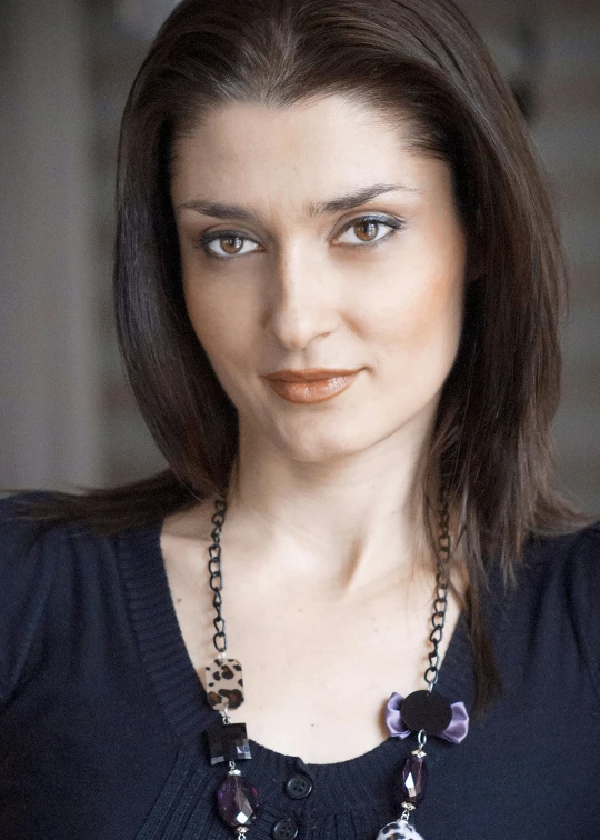 woman with dark shirt looking straight ahead with necklace and large beads on neck