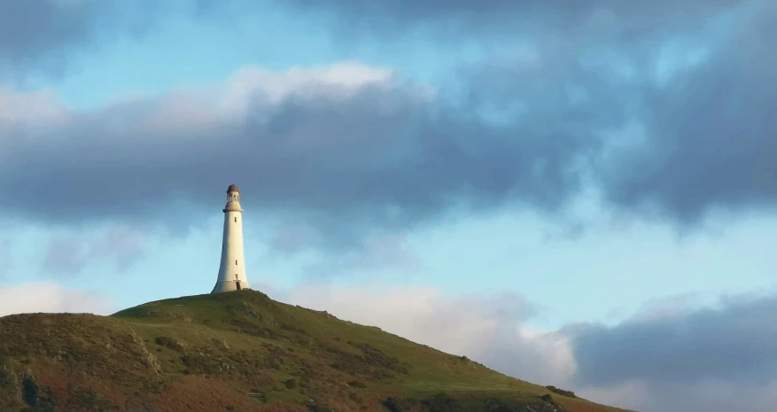 a view of a lighthouse on top of a grassy hill