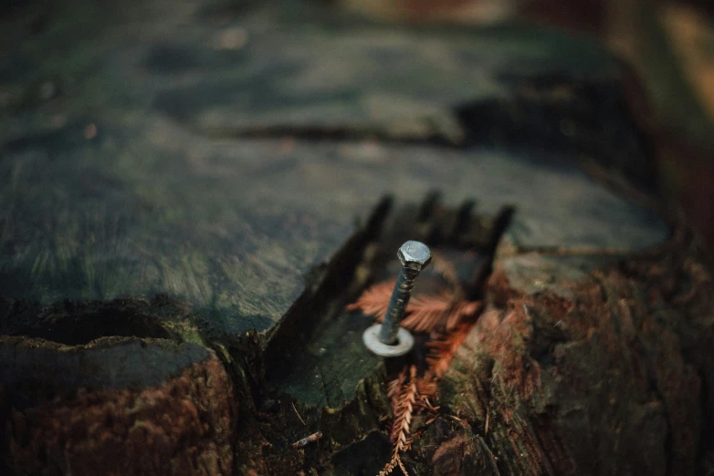 a broken knife and nail sitting on top of a wooden table