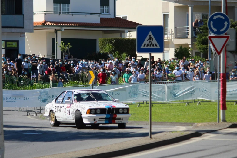 a car making a left turn in front of spectators