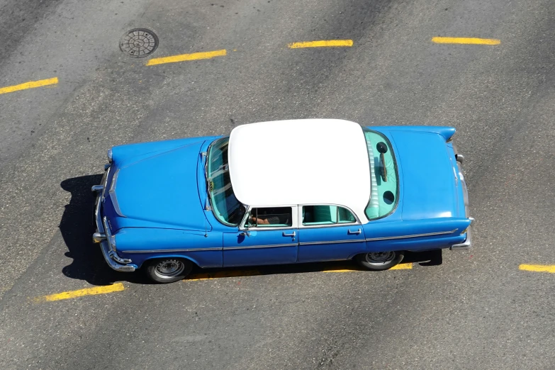 a vintage blue car parked next to a yellow line