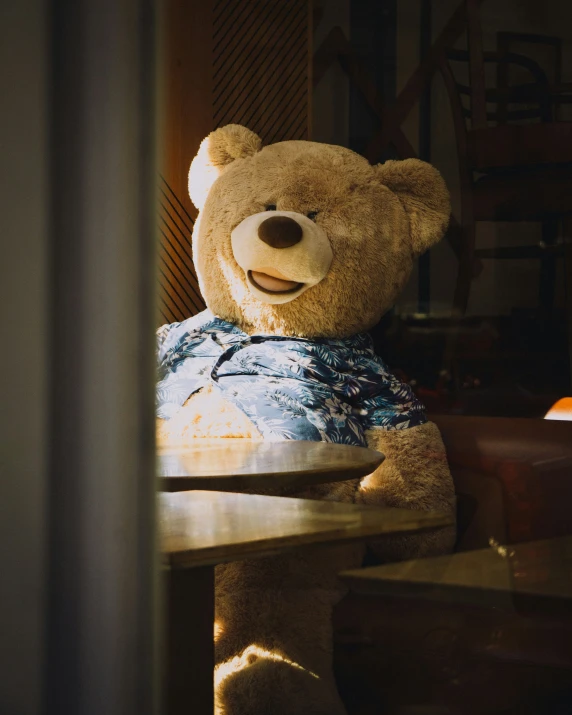 teddy bear sitting at table with blue pillow and brown lamp