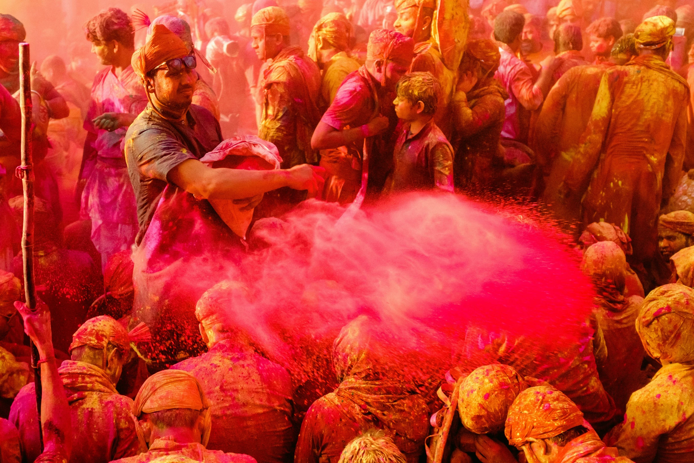 people are gathered with colored powder and throwing them into the air