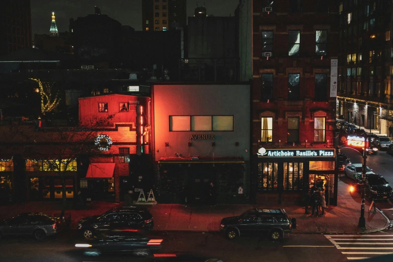 a lit up restaurant with cars driving past in the background