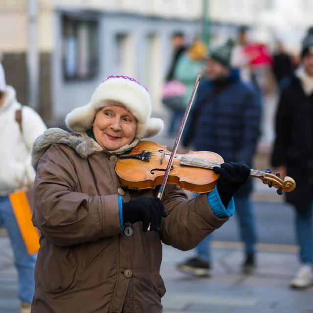 a woman with a furry cap on is playing a violin