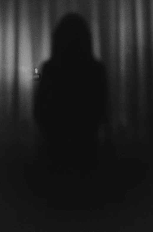 a person is in a dark room behind the curtain