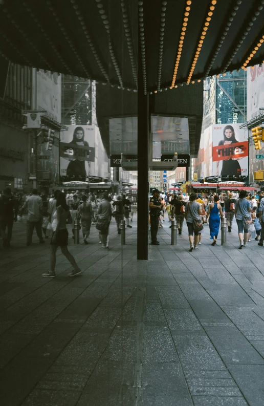 many people walking around an open street in front of tall buildings