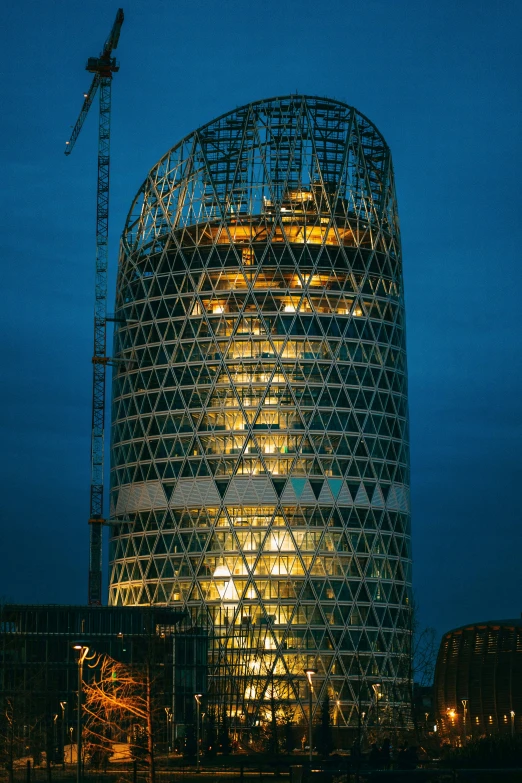 building lit up at night with building and crane in the background