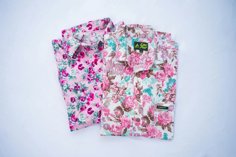 two bright colored flowered shirts, one with pink and green flowers