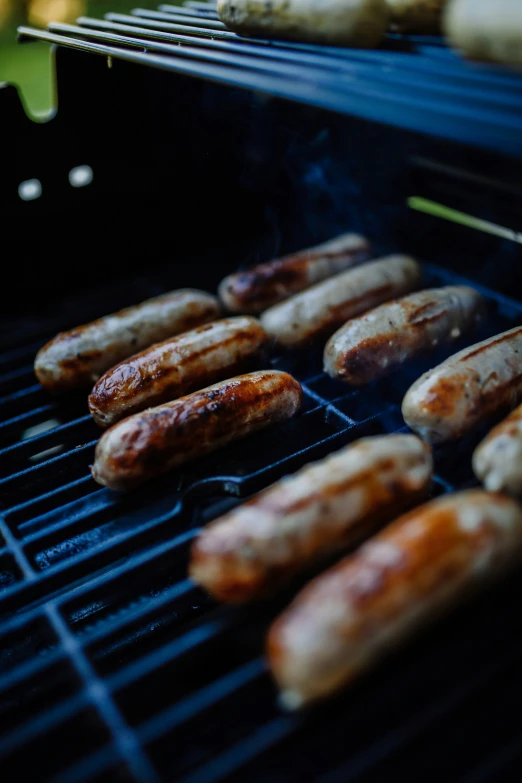 many sausages cooking on an outdoor grill
