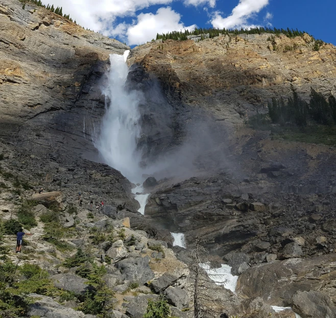 a person taking a picture at the base of the falls