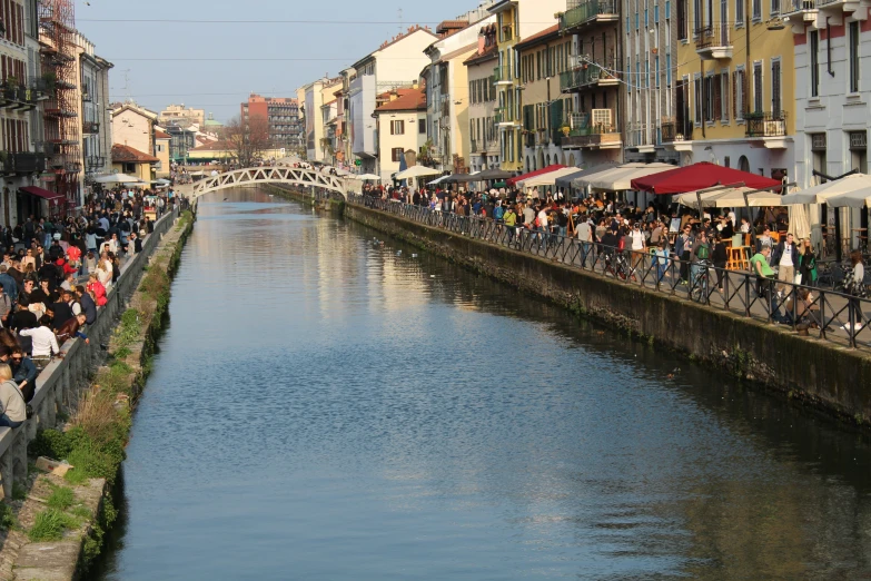 people are sitting at a cafe next to a canal