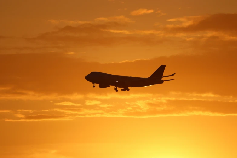 a plane flying at sunset on a cloudy day