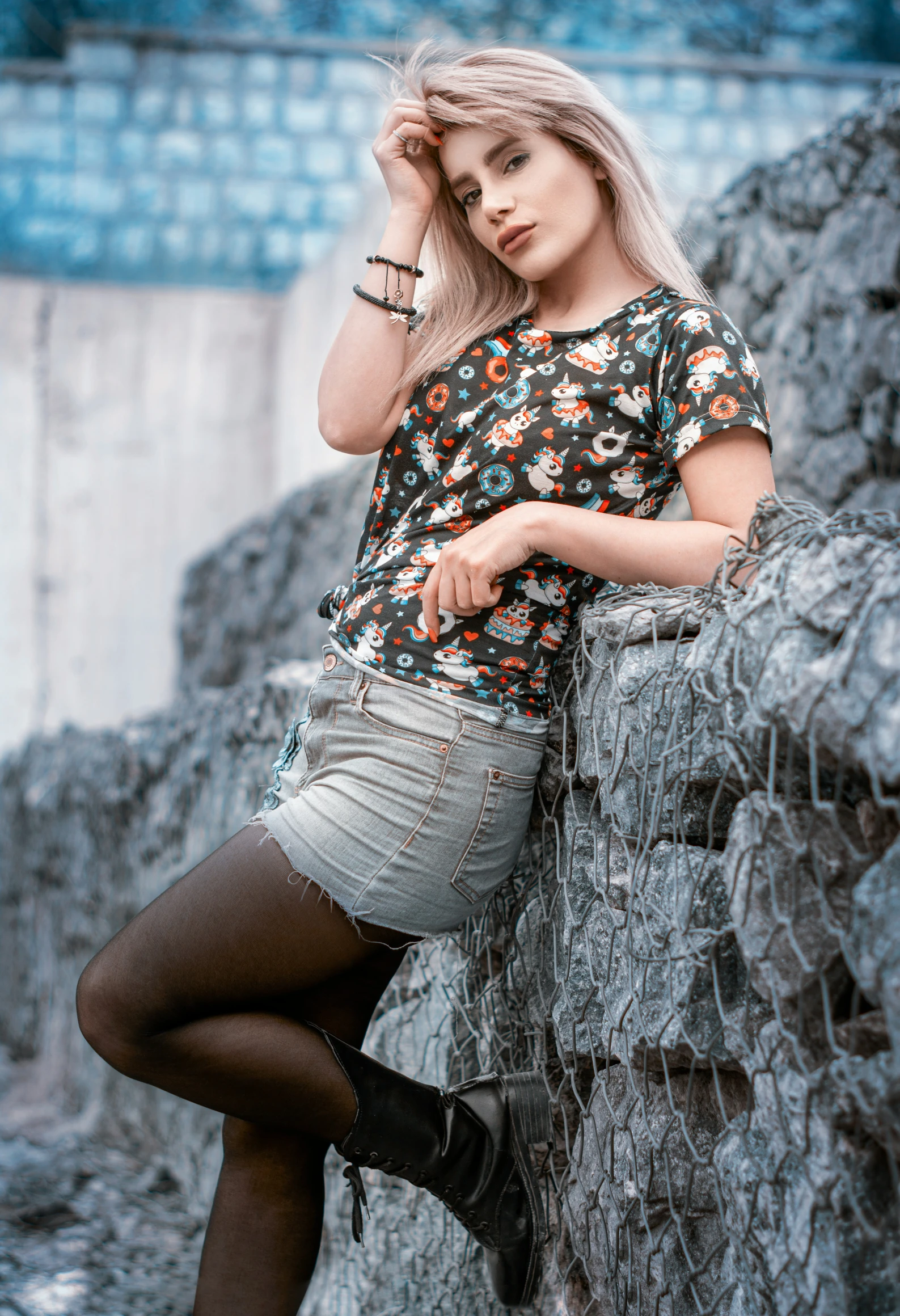 a girl leaning on a stone wall with one hand near her head