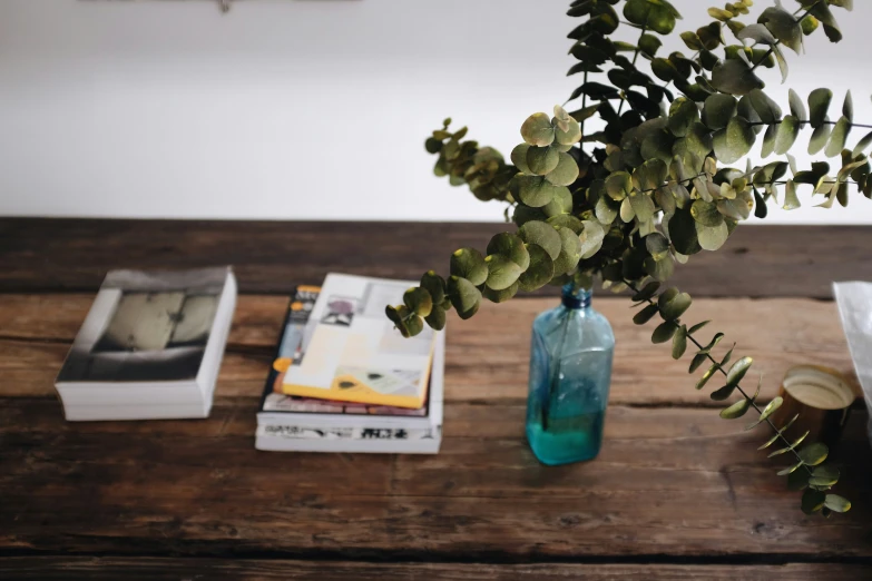 a wooden table with some books and a glass vase