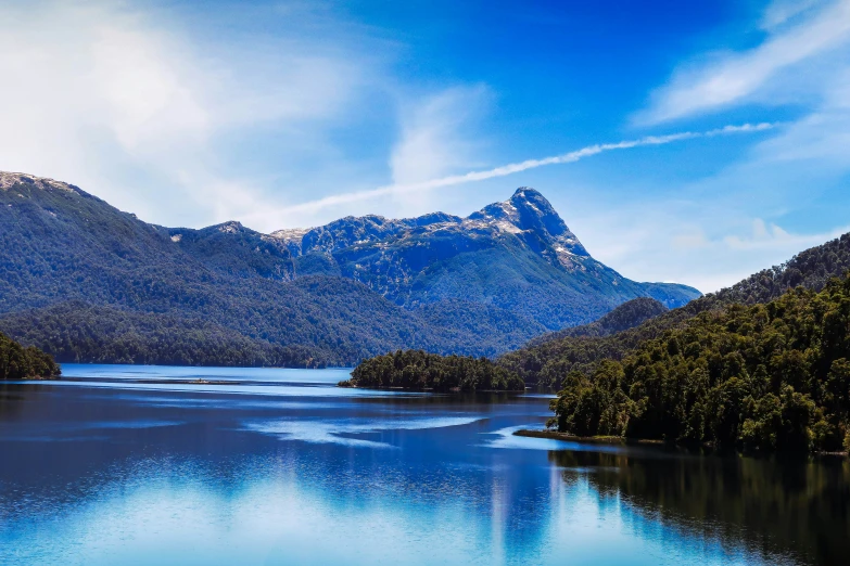 a mountain lake near some trees and blue sky