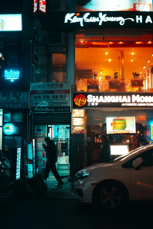 a person walking on the sidewalk by a city store at night