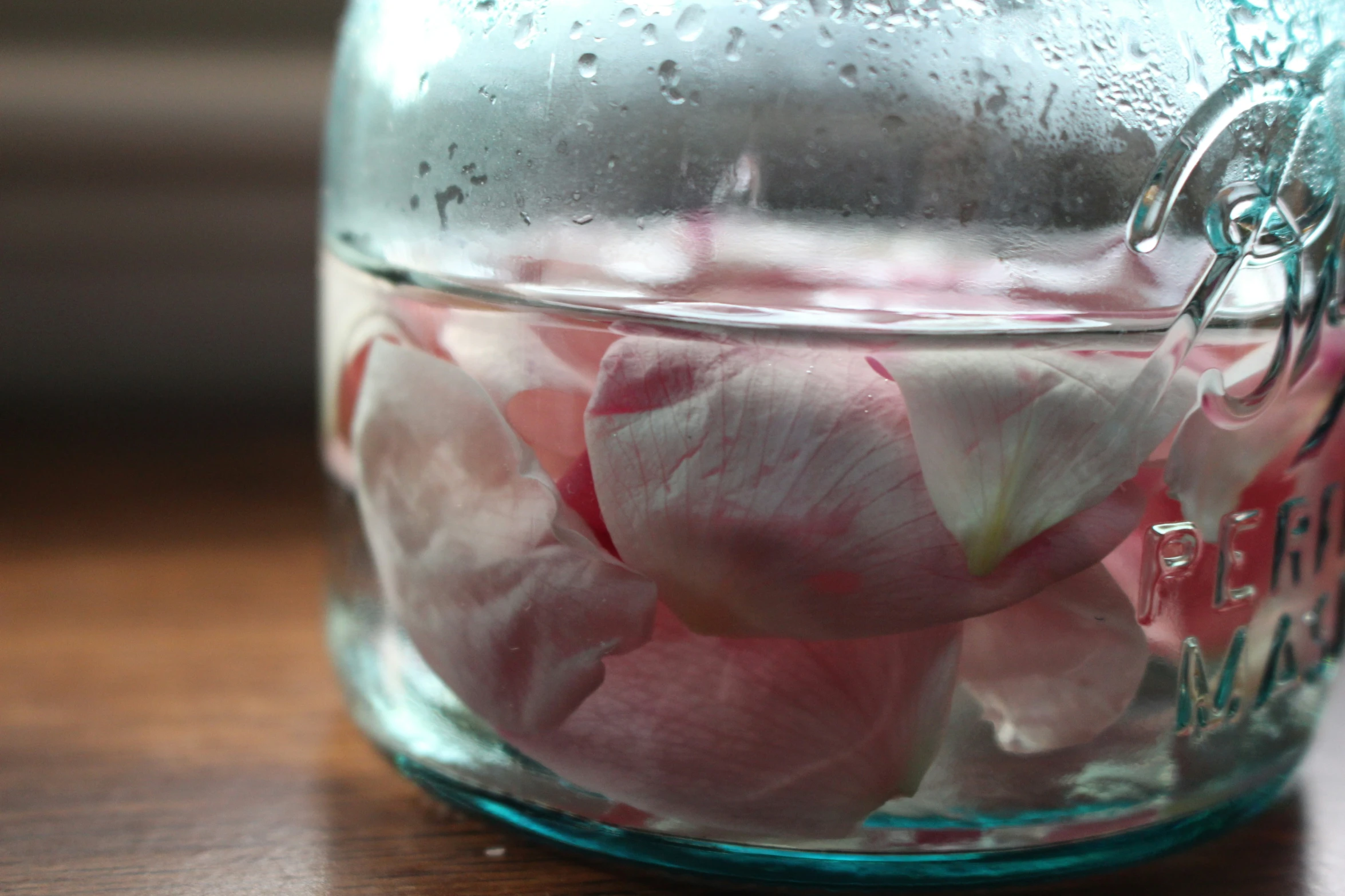 a glass jar with water and pink roses in it