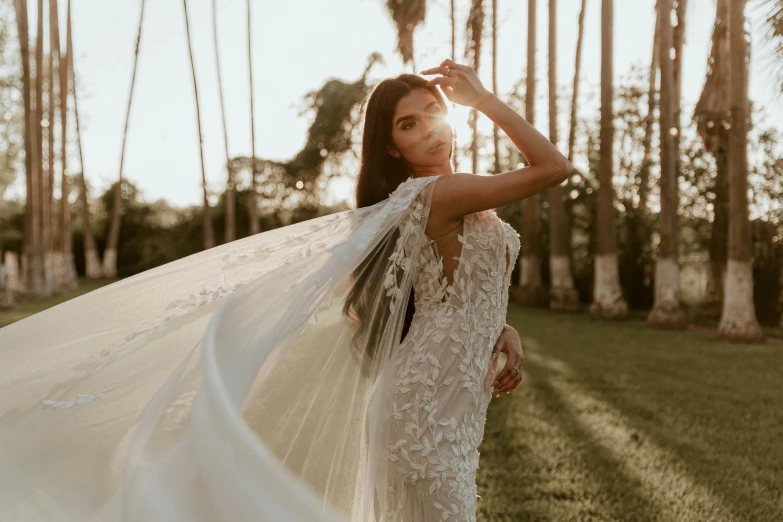 a woman with white veil holding up a wedding dress