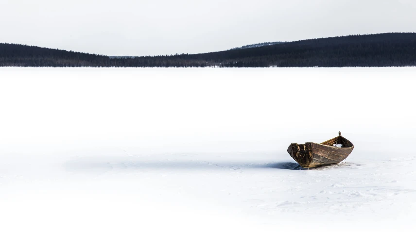 a snow covered boat floating on top of a snow covered field