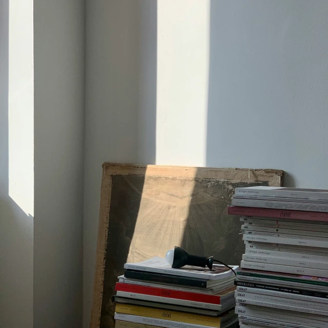 the corner of a room with a chair and a pile of magazines