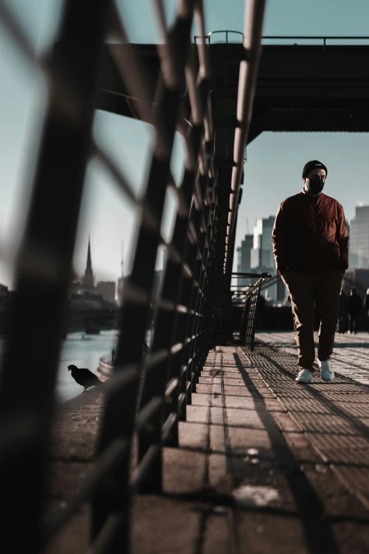 man wearing red jacket and white hat walking through a bridge