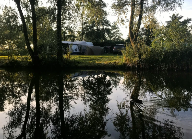 some water bushes trees grass and a trailer