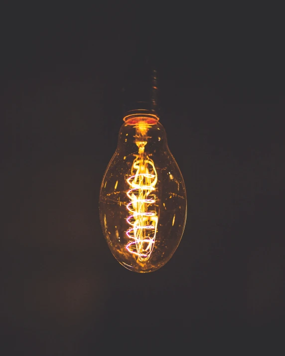 a yellow lit up light bulb on black background