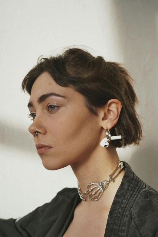 the back view of a woman wearing gold earrings and a grey top