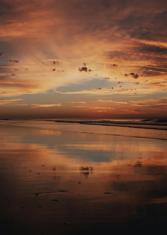 the sunset at the beach has been reflecting off the wet sand