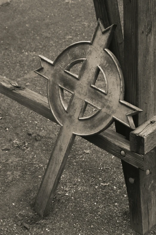 a cross with an old style symbol is in front of a fence
