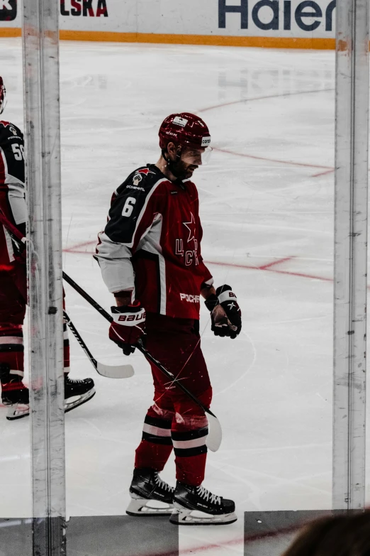 two hockey players in red uniforms walking through a ice rink