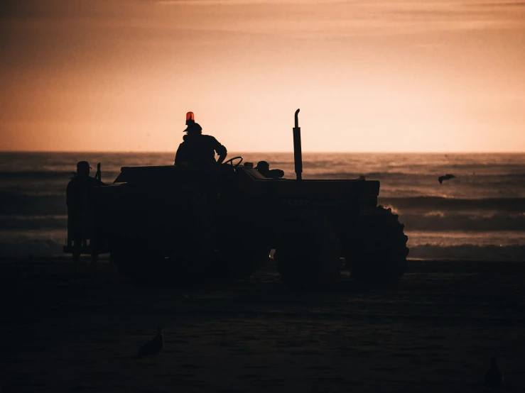 three people on top of a vehicle on the beach