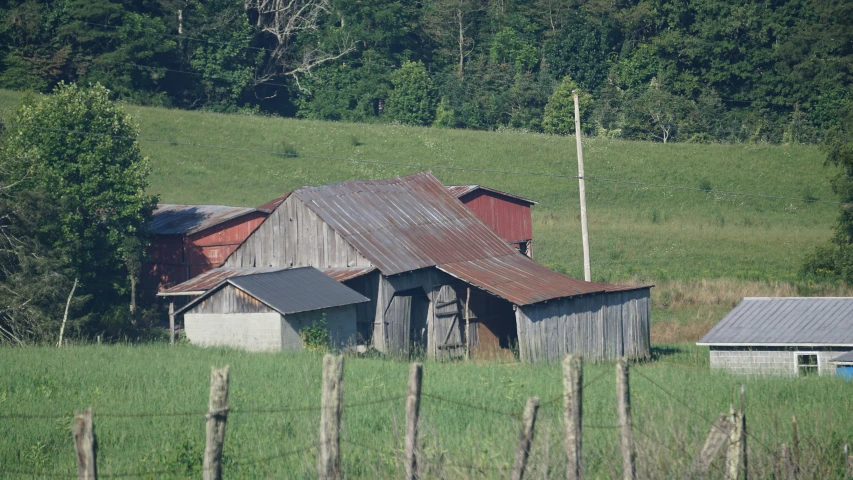 an old barn in the middle of a grassy field