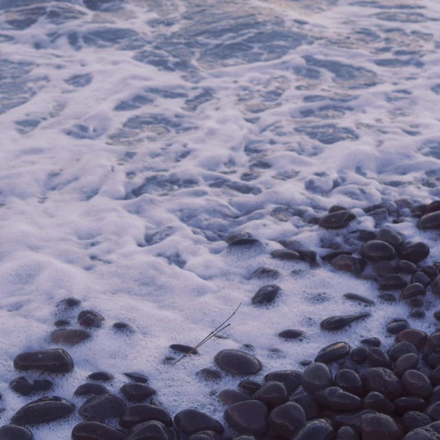 rocks on a beach near the ocean, with waves crashing on them