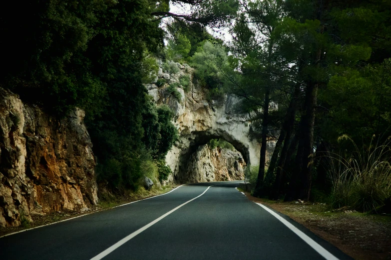 the road is narrow and winding with a tunnel at the end