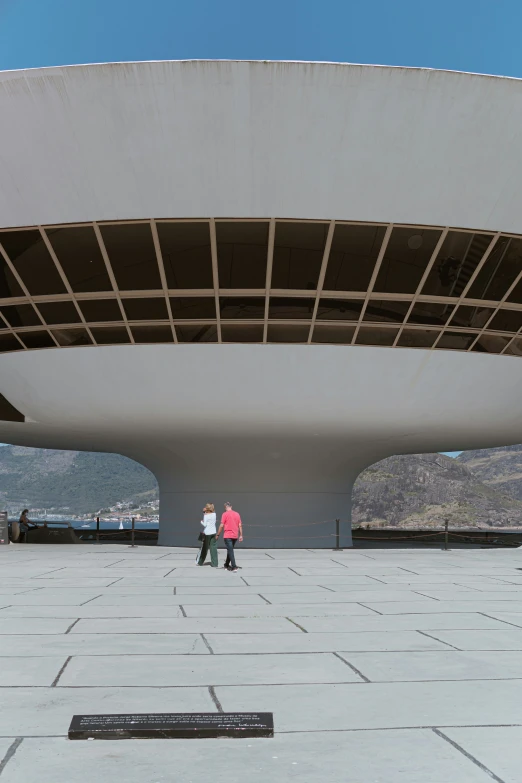 two people standing underneath an open roof with mountains in the distance