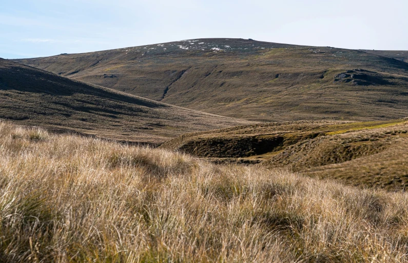 a mountain range with brown grass and mountains