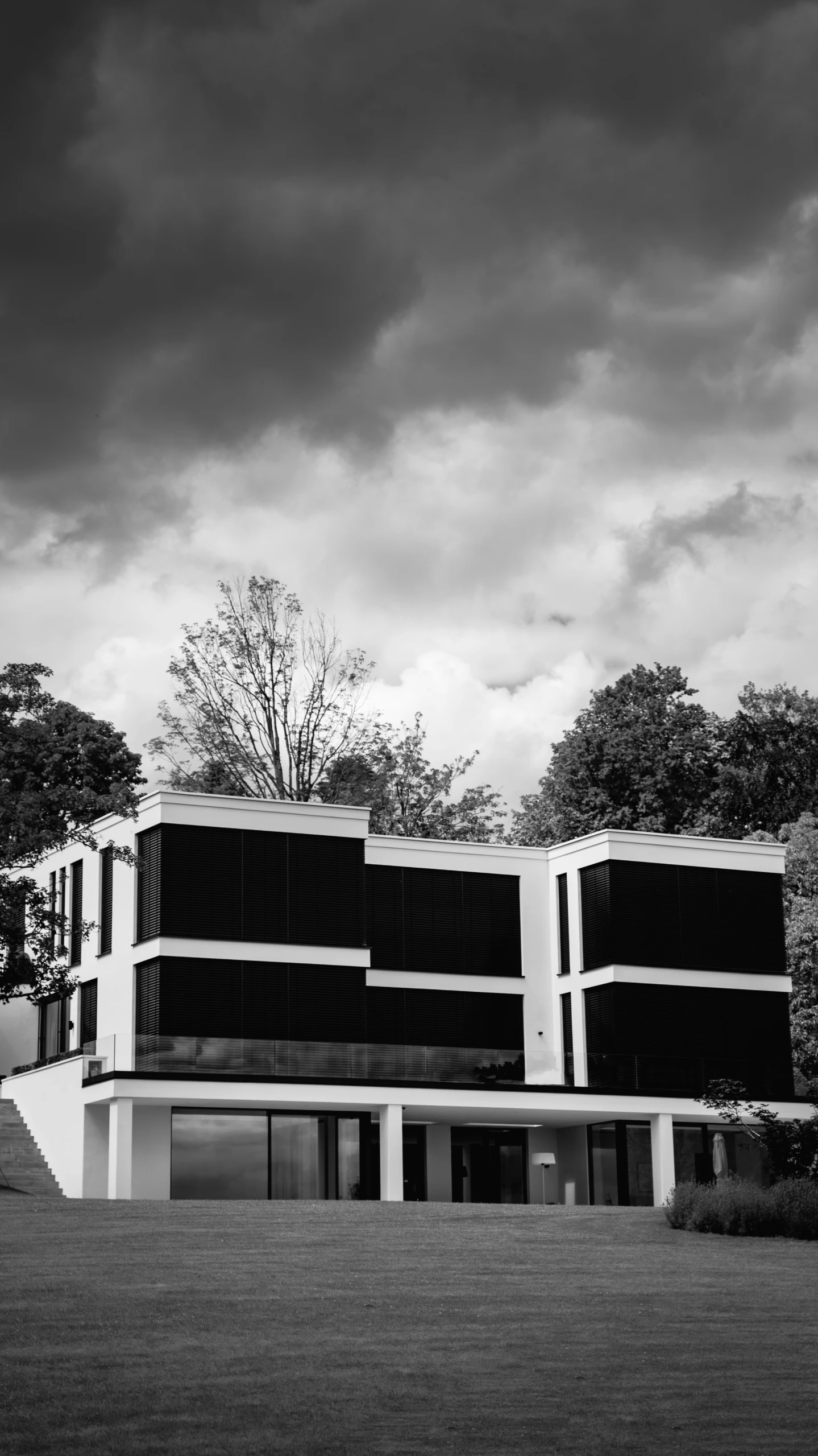 two buildings on grass area near trees with cloudy sky