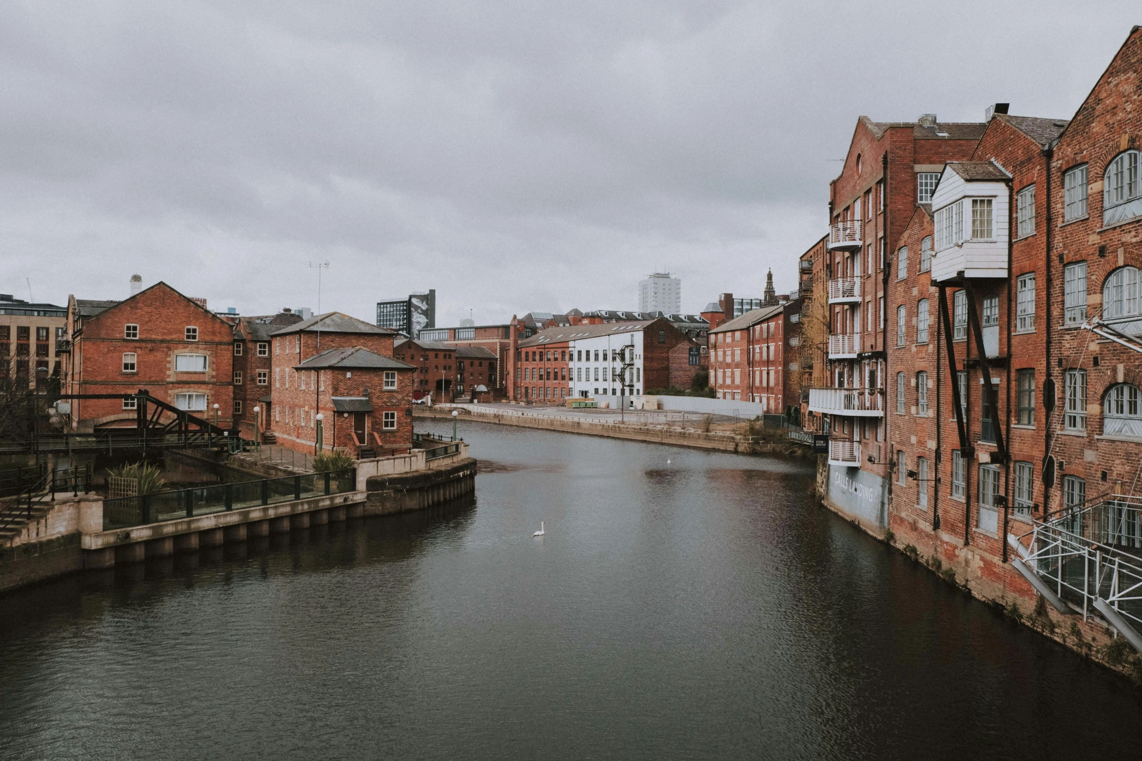 a long waterway between two buildings with two birds swimming on it